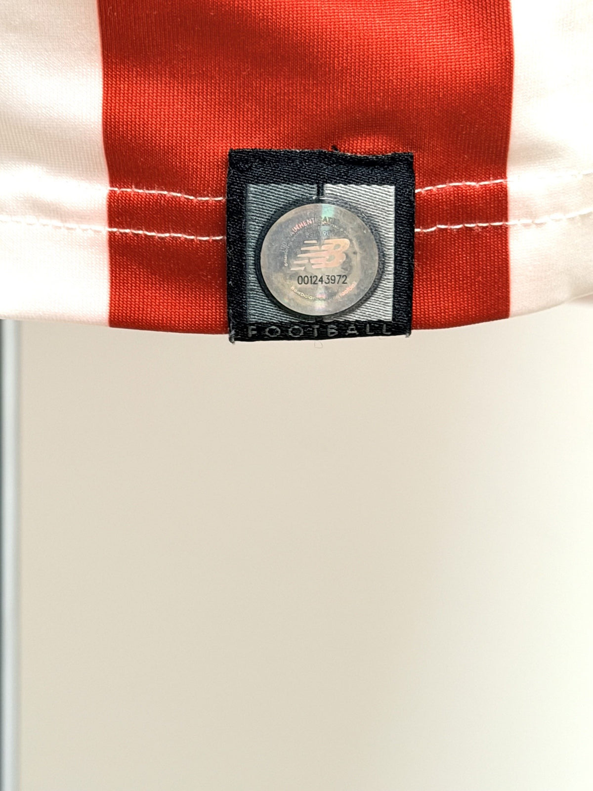 Detalle del sello con holograma NB y número de serie de la camiseta profesional.