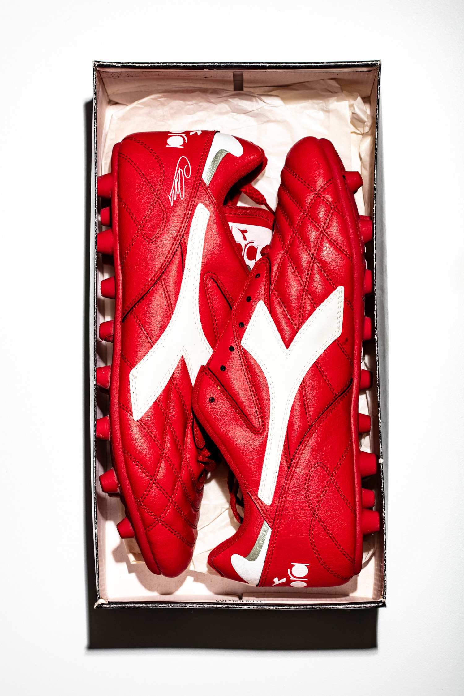 Vista cenital de las botas Diadora Club Pro en color rojo dentro de su caja original.
