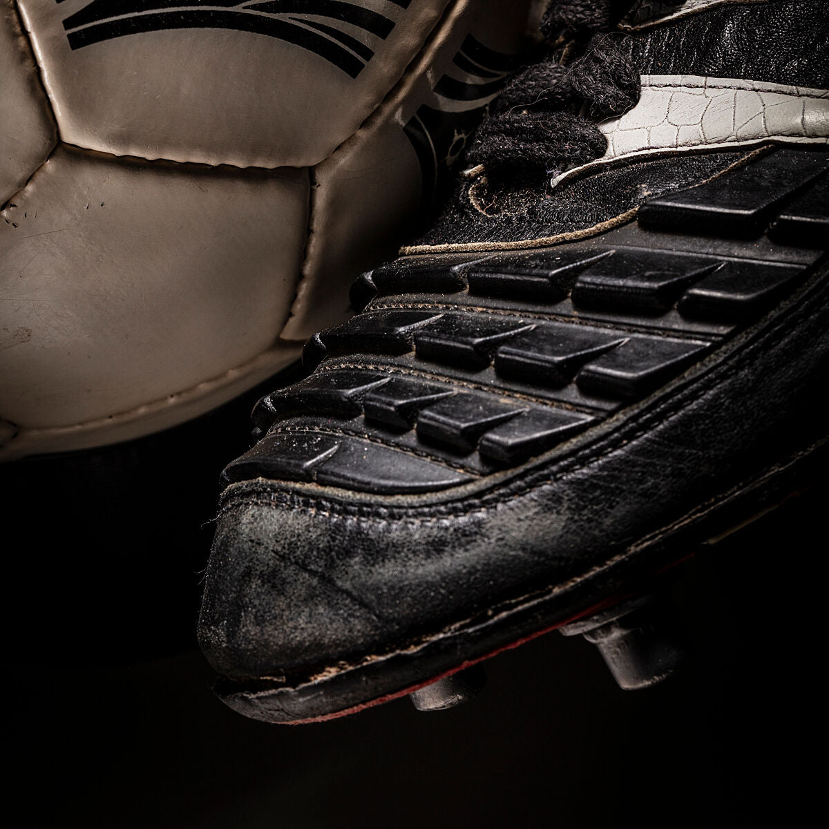 Detalle de un balón Questra de 1994 con una bota izquierda Predator.