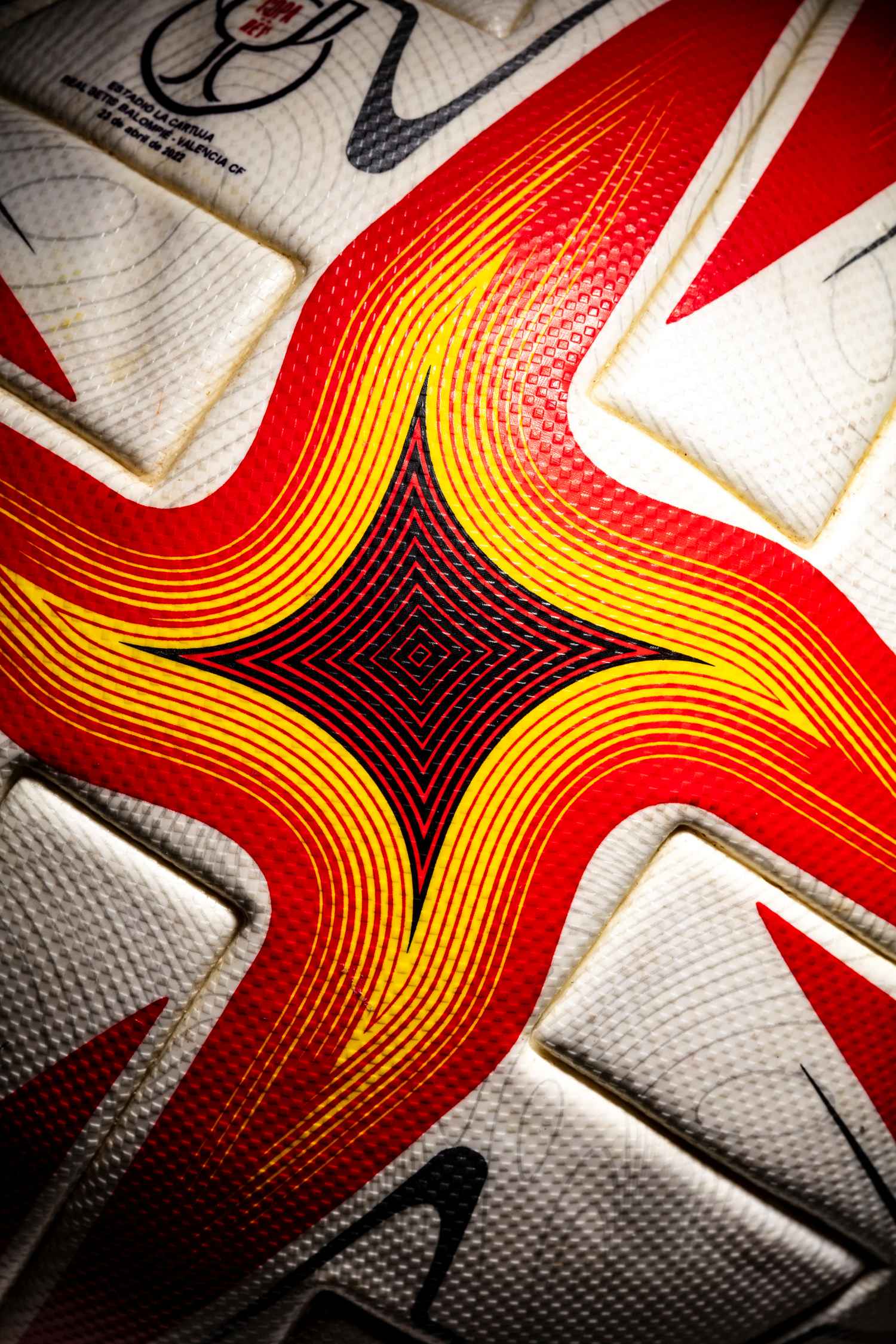 Imagen del diseño del balón con colores muy vivos en rojo, naranja y amarillos. En zona superior se observan las impresiones de los equipos de la final