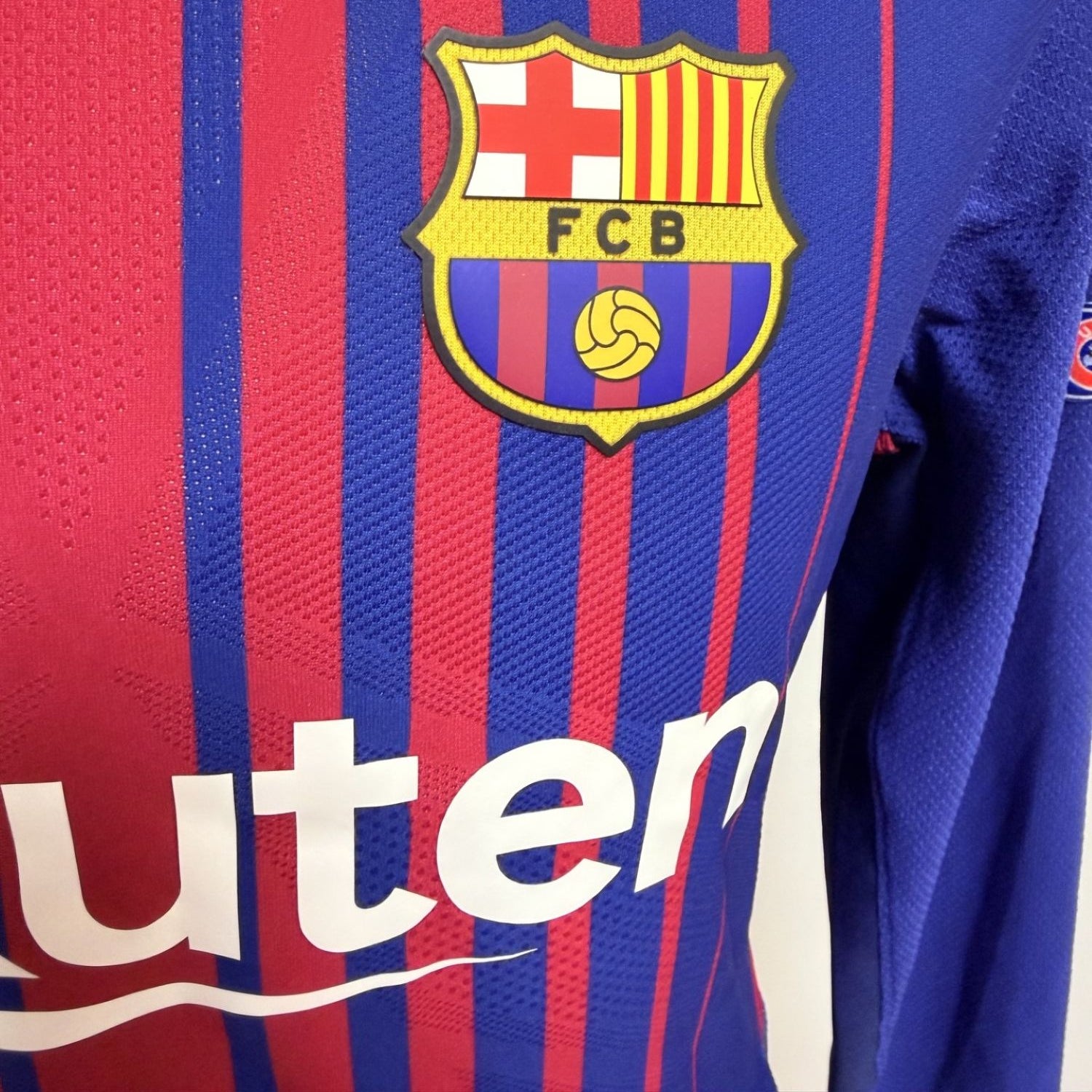 Plano detalle del escudo del FCB, del tejido de la camiseta y separación sobre serigrafía sponsor Rakuten