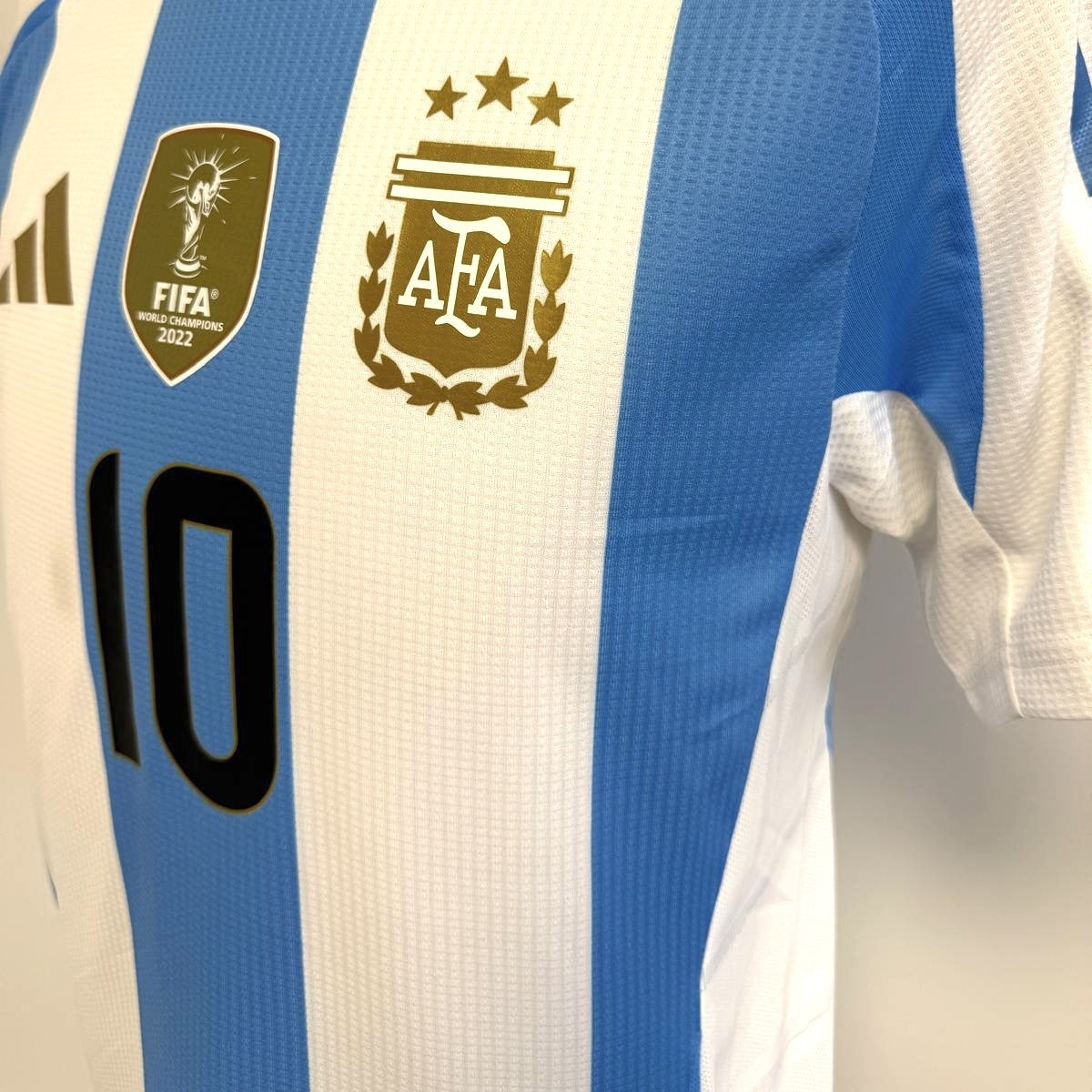Plano detalle con vista en 45º del la zona de escudo AFA, dorsal 10, escudo FIFA Campeones del mundo 2022