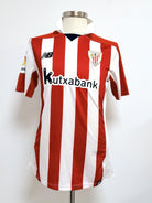 Vista anterior completa, se aprecia el tipo de cuello, escudo, logo marca NB y sponsor Kutxabank