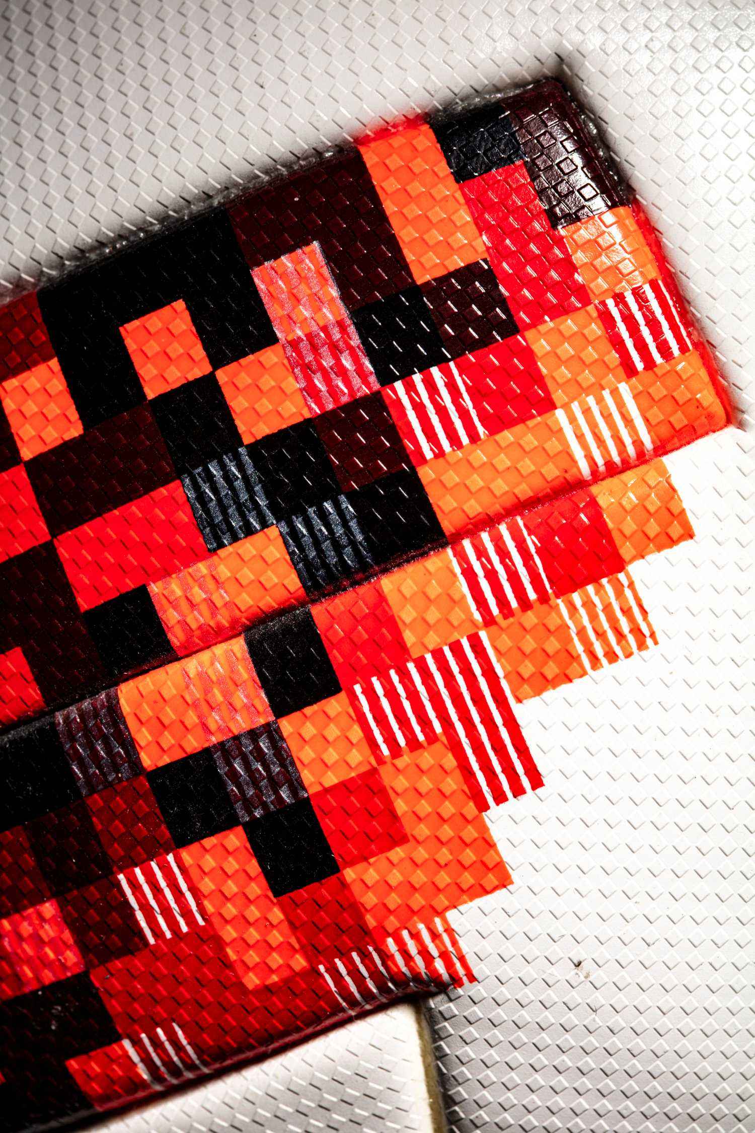 Detalle del diseño con zoom para observar los cuadrados en diversos colores, rojo, naranja y negro.