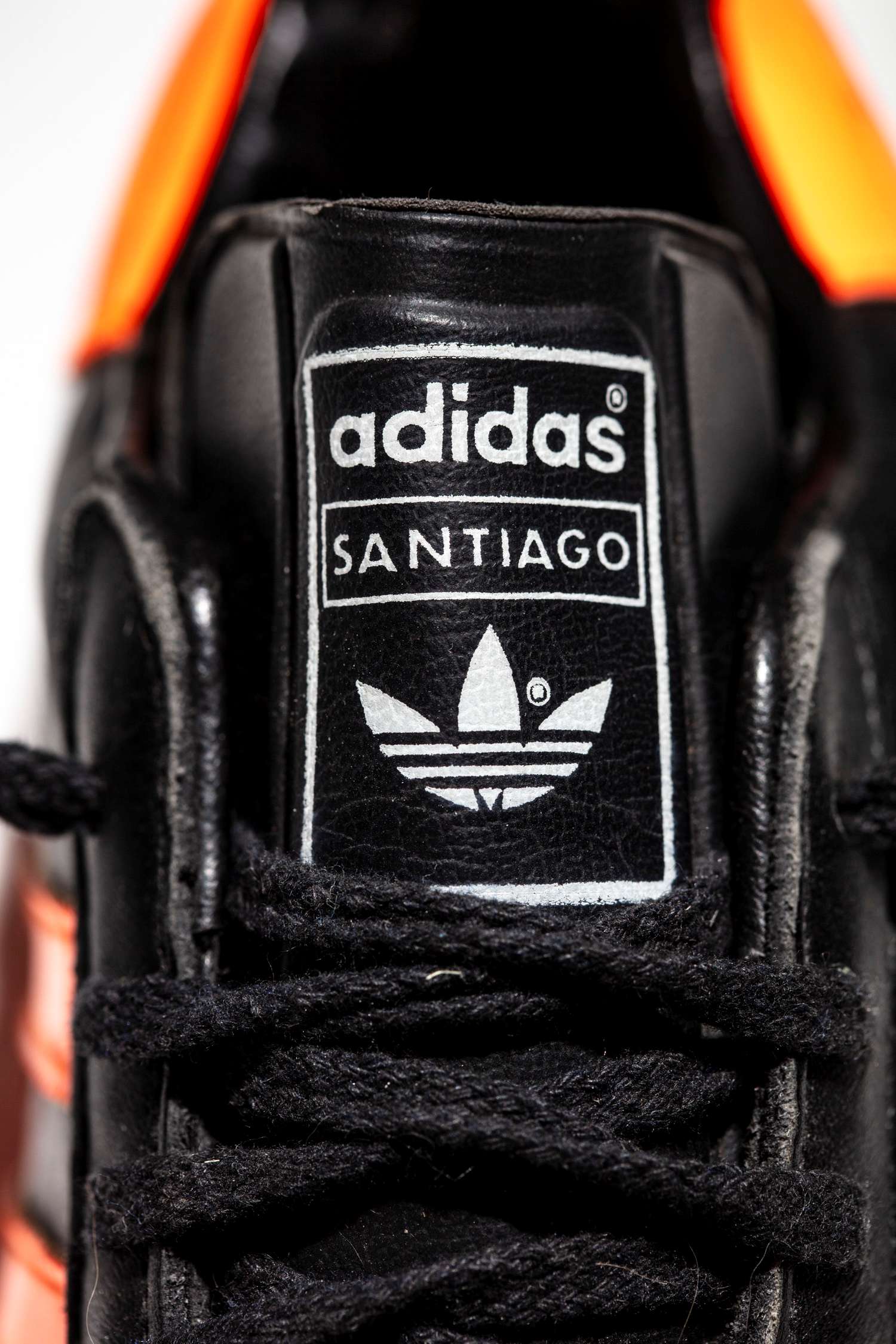 Detalle ampliado del logo adidas y modelo Santiago de lengüeta