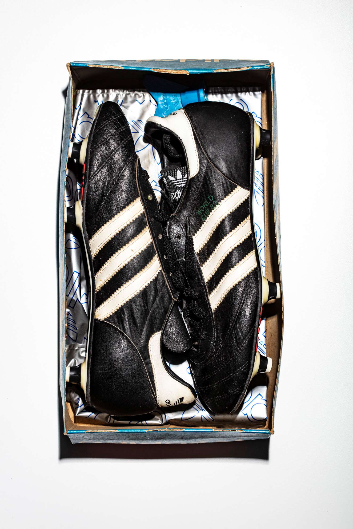 El par de botas sin acordonar en su caja original que conserva la llave de recambio de tacos y la bolsa adidas en su interior.