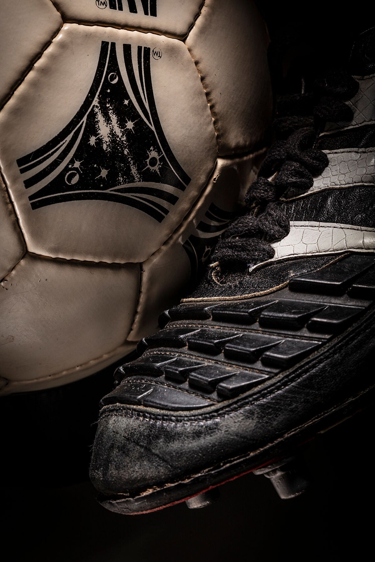 Detalle de un balón Questra de 1994 con una bota izquierda Predator.