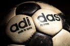Detalle de la inscripción adidas con la separación propia de los balones anteriores a 1975. Se observa el cuero natural con desgaste.