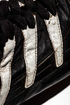 Vista lateral y plano detalle de las tres franjas adidas en color blanco con escamas