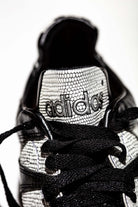 Lengüeta adidas de pequeño tamaño, no flexible y granulado a juego con la franjas adidas.
