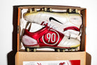 Vista de las dos botas, dentro de su caja original y del icónico logo Total 90