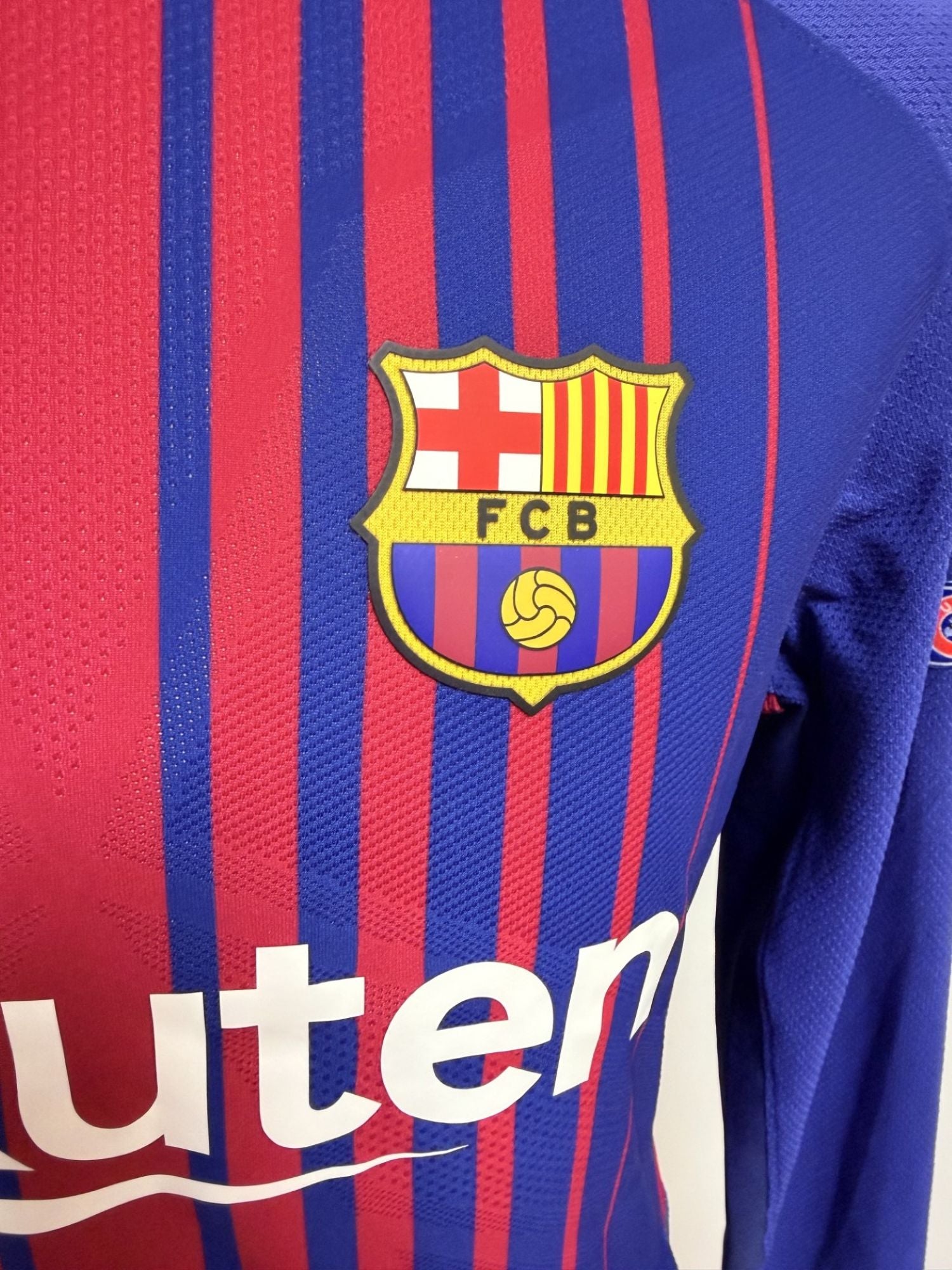 Plano detalle del escudo del FCB, del tejido de la camiseta y separación sobre serigrafía sponsor Rakuten